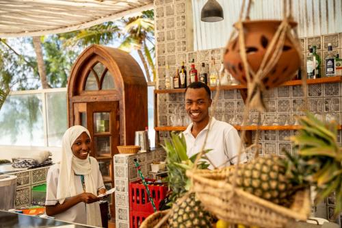 a man and a woman standing in a kitchen at ZAN Orient Beach Hotel in Bwejuu