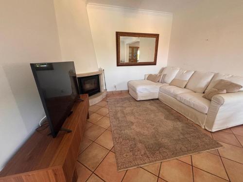 a living room with a white couch and a television at NEW! Casa do Praia Almancil in Almancil