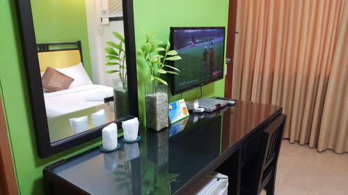 a room with a desk with a television and a bedroom at Residencia Boracay in Boracay