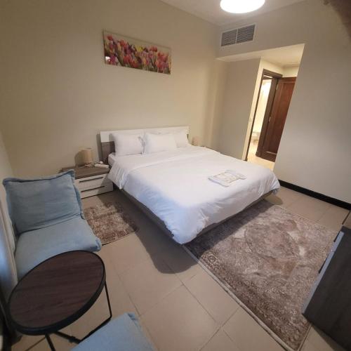 a bedroom with a large white bed and a chair at Marina Deluxe 2, family only in King Abdullah Economic City