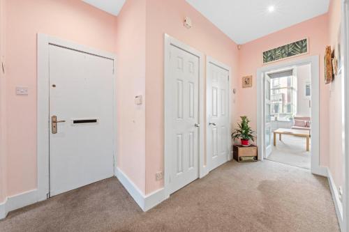 a hallway with pink walls and white doors at Unique Victorian Home in Glasgow in Glasgow