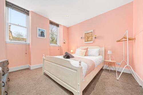 a bedroom with a white bed and pink walls at Unique Victorian Home in Glasgow in Glasgow