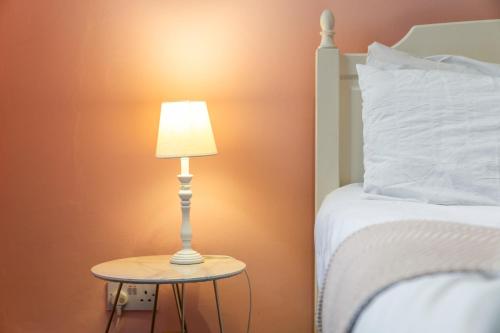 a lamp on a table next to a bed at Unique Victorian Home in Glasgow in Glasgow