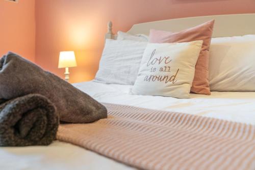 a bed with a pillow that reads love is all around at Unique Victorian Home in Glasgow in Glasgow