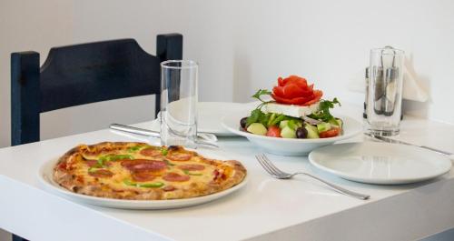 a table with a pizza and a bowl of fruit at Naxos Colosseo in Agios Prokopios