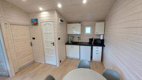 a small kitchen with white cabinets and a table and chairs at Domki SILVER 3 in Jarosławiec