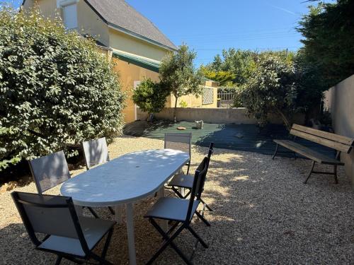 a table and chairs and a bench in a yard at Le Charmant in Port-Bail-sur-Mer