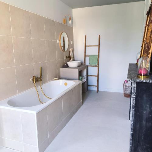 a bathroom with a bath tub and a sink at Gîte de l'épure avec patio in Rémalard en Perche