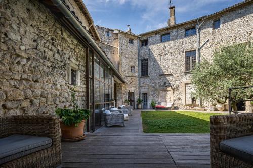 an outdoor patio with wicker chairs and a stone building at La Chapelle sur la Sorgue in LʼIsle-sur-la-Sorgue