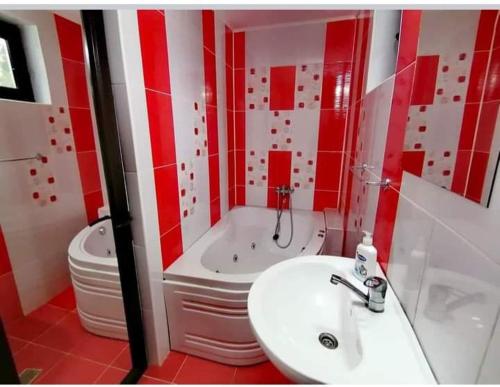 a red and white bathroom with a sink and a tub at Casa Popasul lui Horea in Vartop