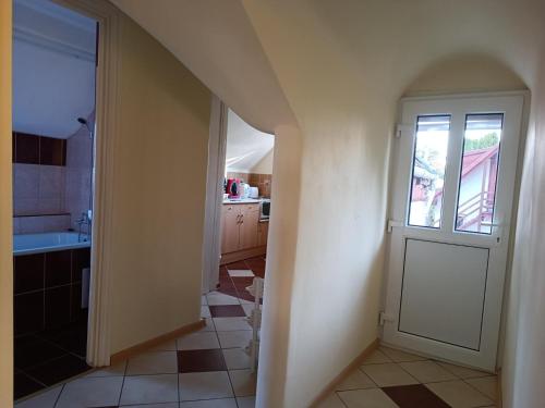 una cocina con una puerta que conduce a un baño en Derű Apartman, en Mezőkövesd