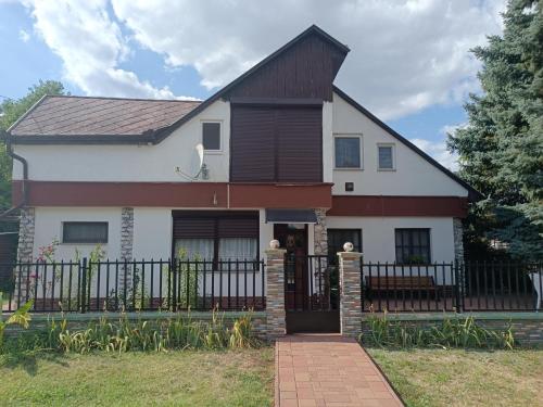 una gran casa blanca con una valla negra en Derű Apartman, en Mezőkövesd