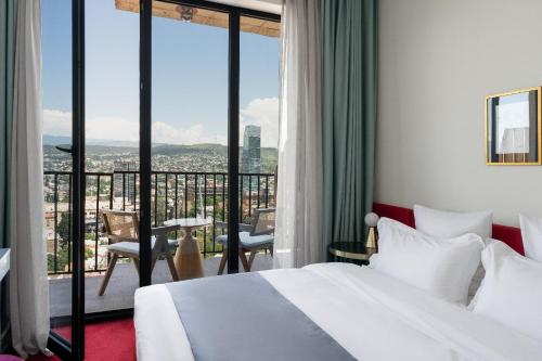 a hotel room with a bed and a balcony at Stars by Castor & Pollux in Tbilisi City