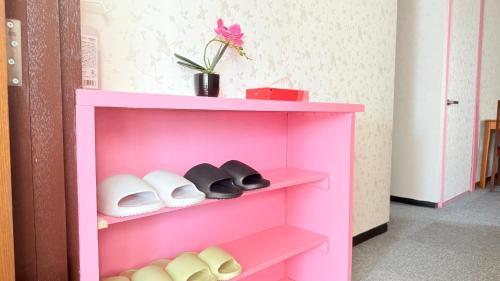 a pink shelf with shoes and a plant on it at 瀬戸内多賀町201 in Kusukamimachi