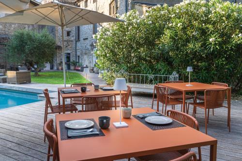 a restaurant with tables and chairs next to a pool at La Chapelle sur la Sorgue in LʼIsle-sur-la-Sorgue