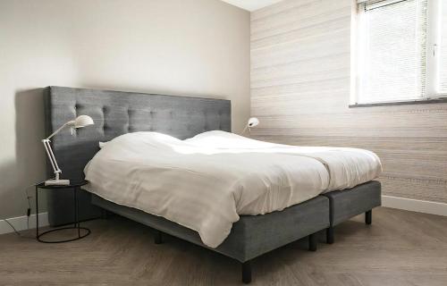 a bedroom with a large bed with a gray headboard at Z Luxe Villa Bouwlust in De Cocksdorp