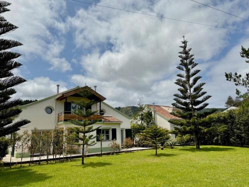 a white house with trees in the yard at Casa dos Netos - Garden & Lake III (Sete Cidades) in Sete Cidades