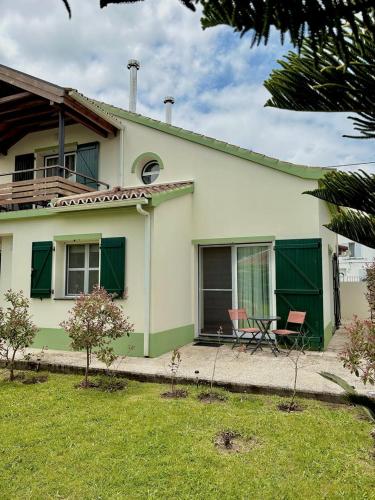 a green and white house with a table and chairs at Casa dos Netos - Garden & Lake III (Sete Cidades) in Sete Cidades