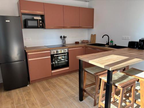 Una cocina con gabinetes marrones y una mesa de madera y un refrigerador. en Idéal pour un séjour à Bordeaux, en Blanquefort