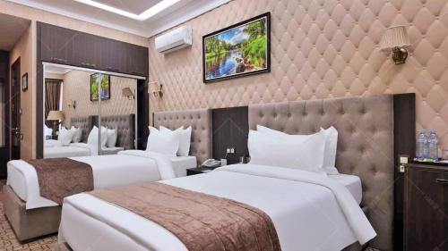a hotel room with three beds and a wall at Mansion Hotel in Stantsiya Kyzyl-Tukumachi