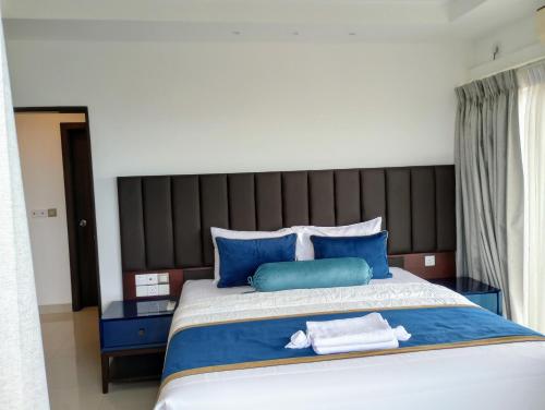 a bedroom with a large bed with blue pillows at OCEAN BREEZE - WAVES LUXURY CONDO in Negombo