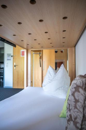 a bed with white sheets and pillows in a room at Schäfle Feldkirch-Altenstadt in Feldkirch