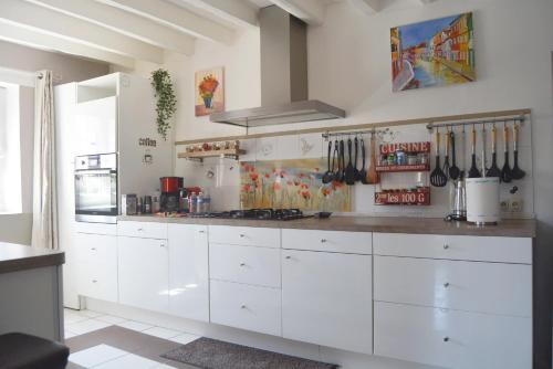 a kitchen with white cabinets and utensils on the wall at La Serenidad in Denonville