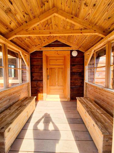 a wooden porch with benches and a wooden door at Highland Warmia - Gospodarstwo agroturystyczne in Jeziorany