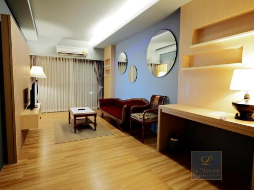 a living room with a red couch and a mirror at Le Naview @Prasingh in Chiang Mai