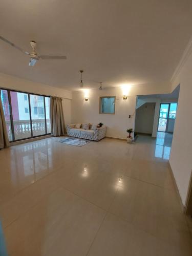 an empty living room with a couch and windows at Outstay Executive Apartments in Navi Mumbai