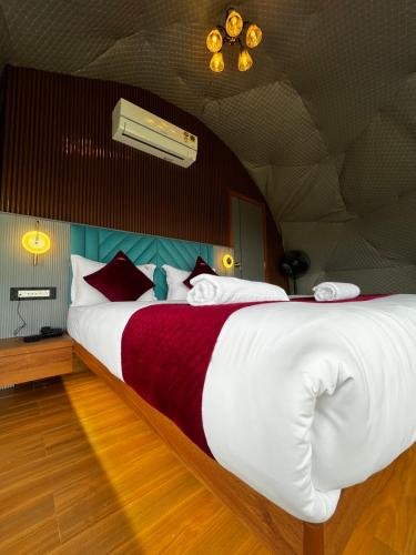 a bedroom with a large bed with red and white sheets at Sovas Nature Hideout in Kolvan