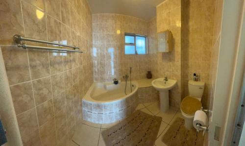 a bathroom with a tub and a toilet and a sink at Unit 102 Warnadoone in Kingsburgh