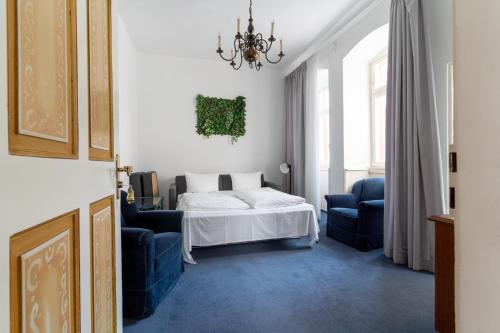 a bedroom with a bed and two blue chairs at Hotel zum Ritter in Heidelberg