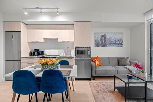 a kitchen and living room with a table and blue chairs at New Modern 1Bd & Den in Downtown Toronto in Toronto