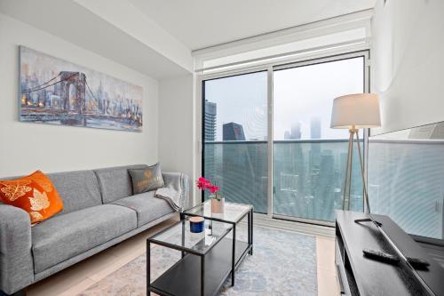 a living room with a couch and a large window at New Modern 1Bd & Den in Downtown Toronto in Toronto