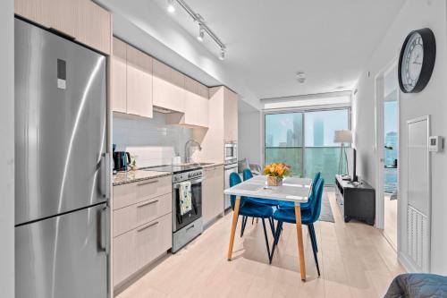 a kitchen with a table and a refrigerator at New Modern 1Bd & Den in Downtown Toronto in Toronto