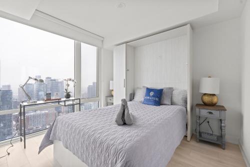 a white bedroom with a bed and a large window at New Modern 1Bd & Den in Downtown Toronto in Toronto