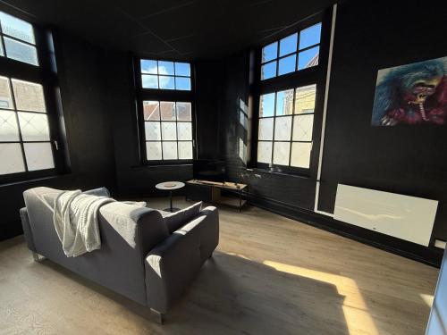 a living room with a couch and some windows at La Symphonie 2 Charmant appartement en centre-ville in Gravelines