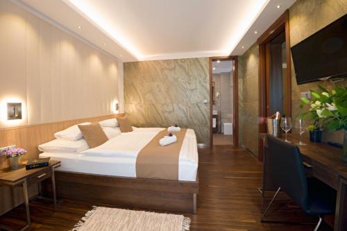 a bedroom with a bed and a desk and a television at Hotel Bartoš in Frenštát pod Radhoštěm