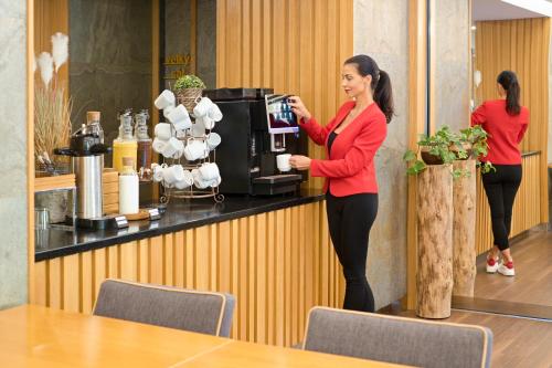 a woman standing at the counter of a coffee shop at Hotel Bartoš in Frenštát pod Radhoštěm