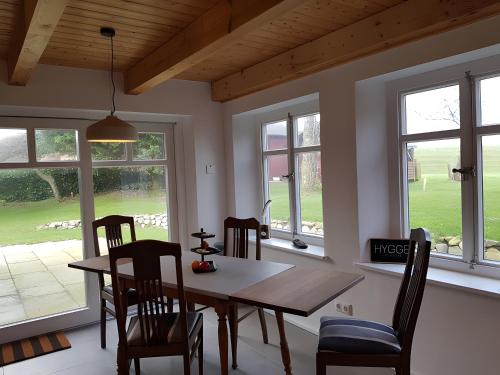 a dining room with a table and chairs and windows at Schäferhaus in Hemme