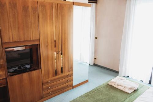 una camera da letto con TV e armadio in legno di Hotel Terme Marconi a Montegrotto Terme