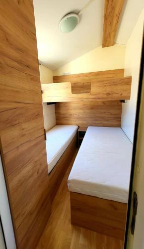a small room with two beds and wooden walls at Stone Haven Mobile Home - Senj in Volarice