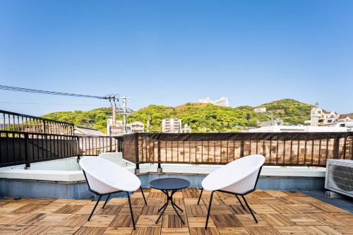 a balcony with three chairs and a table on a roof at SecretBaseMARUYAMA in Nagasaki