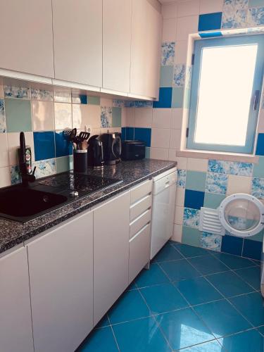 a kitchen with white cabinets and blue tiles at Beautiful Apartment In Albufeira Marina in Albufeira
