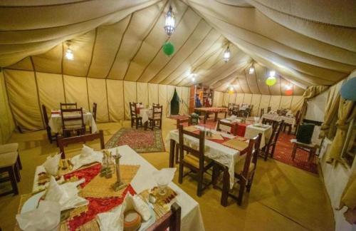 una tenda con sala da pranzo con tavoli e sedie. di Fantastic luxury Desert camp a Merzouga