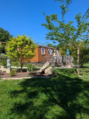 a log cabin in a yard with a tree at Mobil home climatisé avec piscine in Viviers