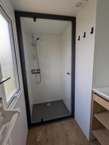 a shower with a glass door in a bathroom at Mobil home climatisé avec piscine in Viviers