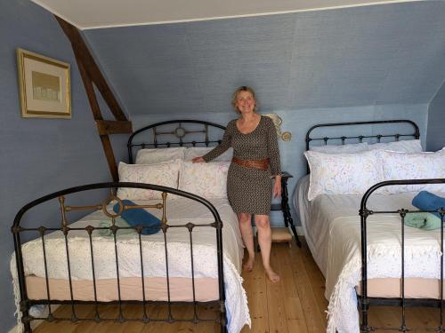 a woman standing in a bedroom with two beds at La Jeannette in Vains