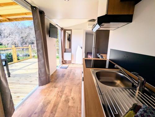 a kitchen with a sink and a wooden floor at Mobil home climatisé avec piscine in Viviers
